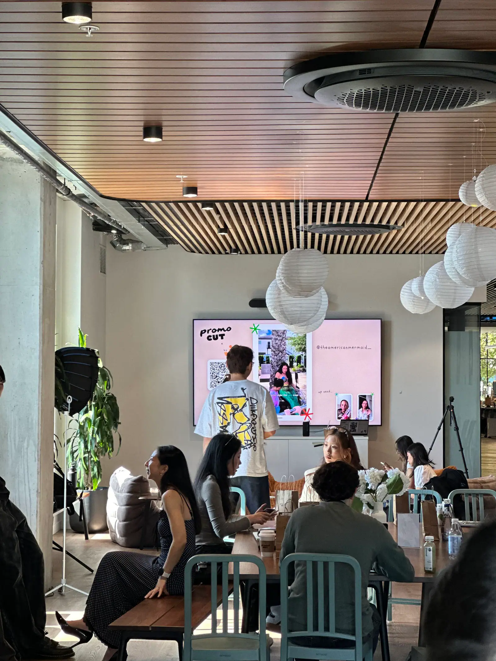 Guests gathered at the PromoCut x Cafe Jœ creator event while a presenter stands in front of a PromoCut display