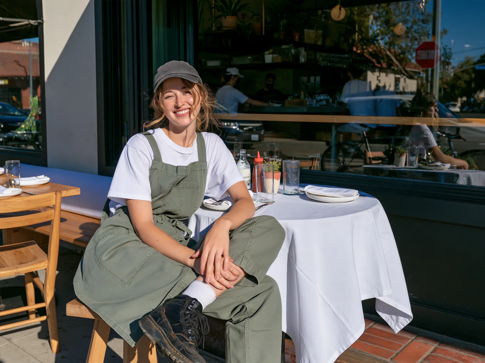 A smiling restaurant worker seated outside at a table